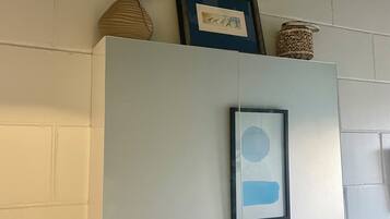 A white cabinet with a framed picture and a small vase with a plant on top.
