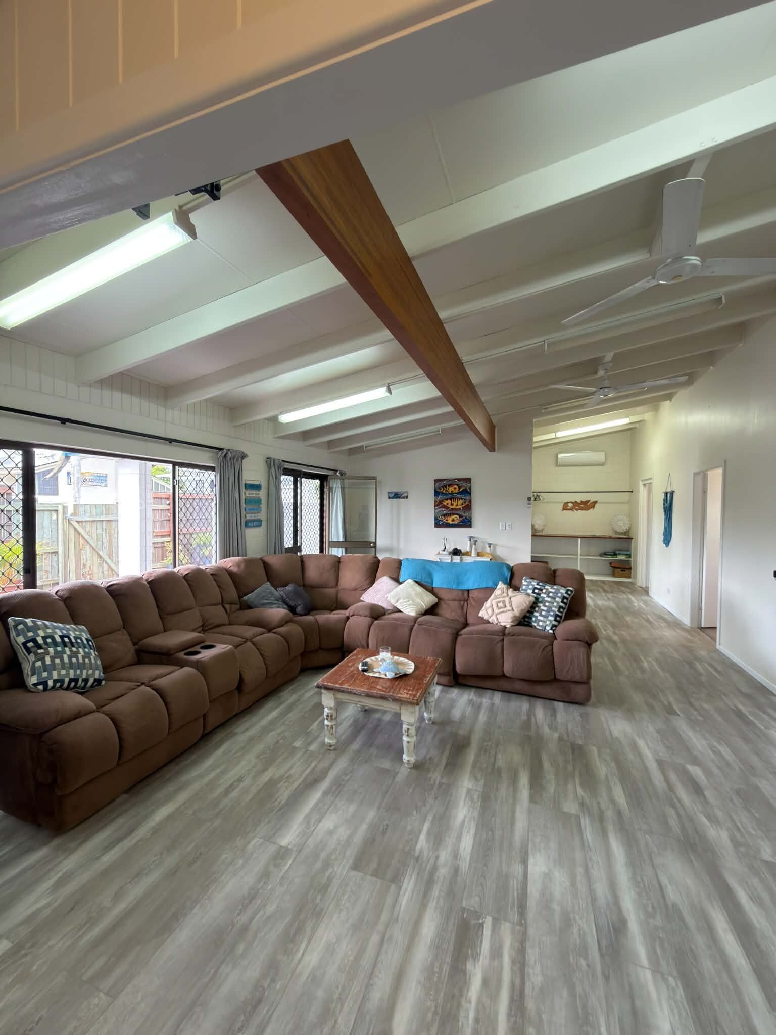A spacious living area with a large L-shaped sectional sofa, a small coffee table, and a ceiling fan.