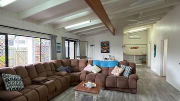 A spacious living area with a large L-shaped sectional sofa, a small coffee table, and a ceiling fan.