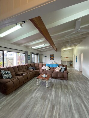 A spacious living area with a large L-shaped sectional sofa, a small coffee table, and a ceiling fan. - Superb 3-bedroom house with AC in charming Iluka (Iluka)