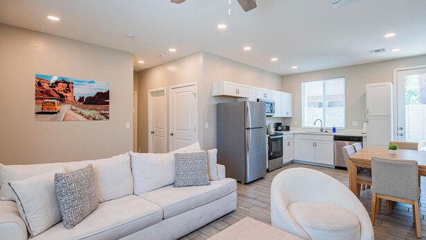 A modern kitchen with white cabinets, a stainless steel refrigerator, and a dining area with a wooden table and chairs. - The One 314 (Glendale)