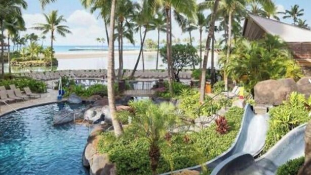 Ein Pool mit Rutsche, Palmen und Blick auf den Strand.
