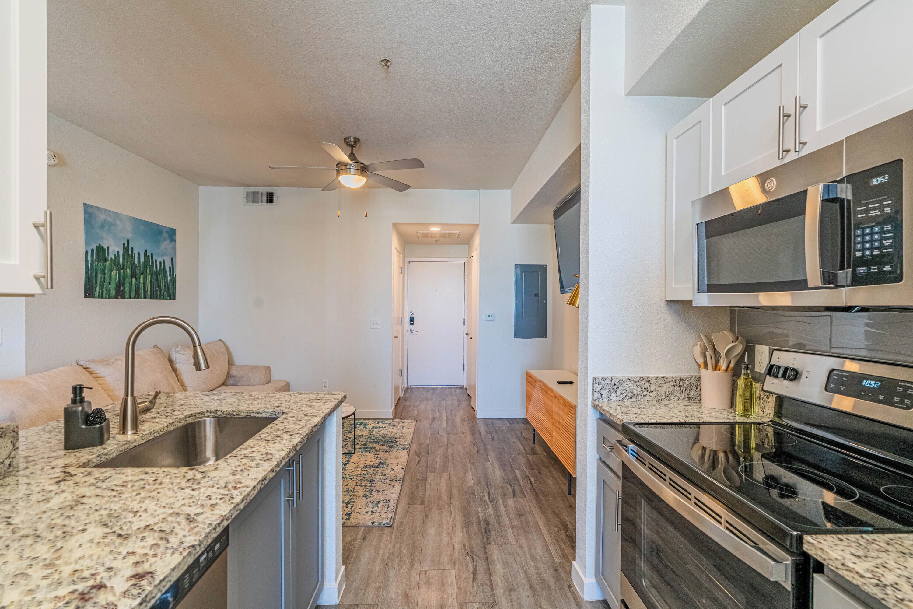 A kitchen with a granite countertop, stainless steel sink, microwave, and stove.