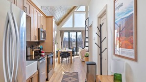 Une cuisine moderne avec des meubles en bois, des appareils électroménagers en acier inoxydable et un coin repas offrant une vue agréable.