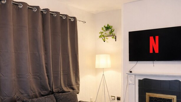 A modern living room with a sectional sofa, a small round table, a floor lamp, a fireplace, and a mounted TV. - Long Contractor Stays - HS2 NEC BHX Parking Wifi Netflix Discounts Offered (Birmingham)