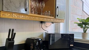 A kitchen with a marble backsplash, a wooden shelf with glassware, a toaster, a microwave, and a window with a plant. - Long Contractor Stays - HS2 NEC BHX Parking Wifi Netflix Discounts Offered (Birmingham)