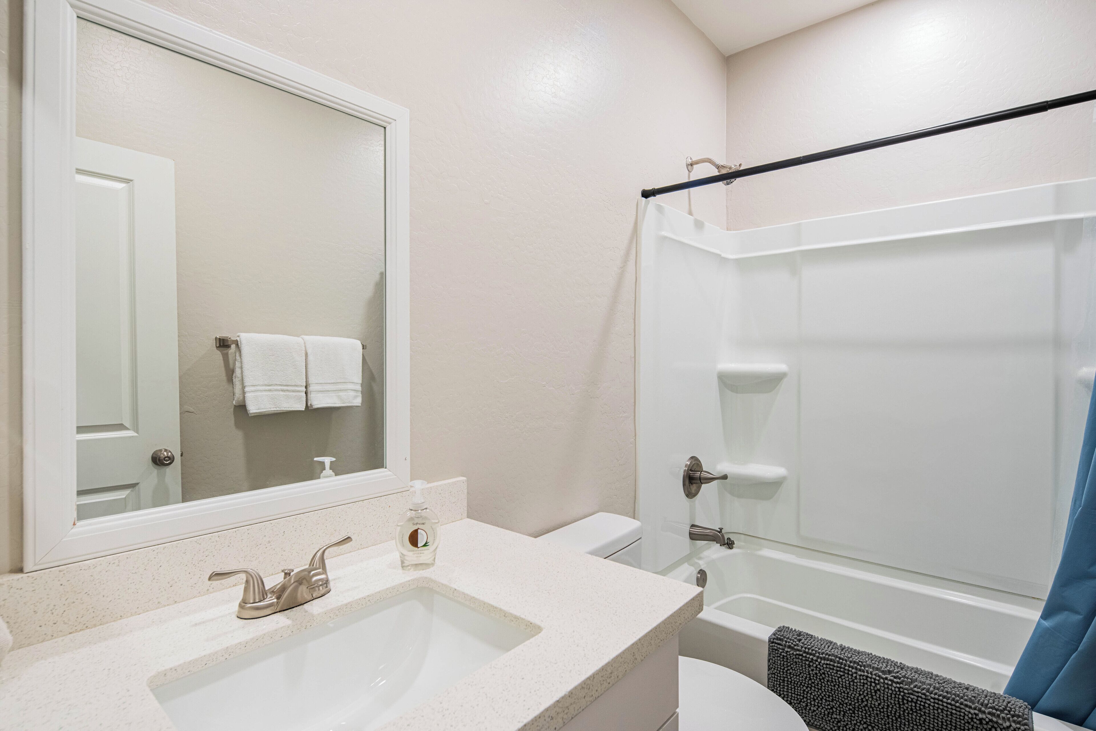 A bathroom with a sink, mirror, and shower.