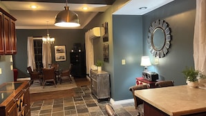 A dining area with a table and chairs, a kitchen counter, and a large mirror on the wall.