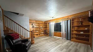Un vaste salon doté d’un escalier en bois, d’un canapé en cuir et de bibliothèques intégrées.