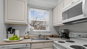 Una cocina moderna con armarios blancos, lavavajillas, estufa y microondas.