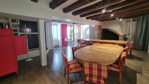 A spacious dining area with a wooden table and plaid chairs, a red cabinet, and a stone fireplace. - Gîte with swimming pool at the gateway to the Morvan - Up to 15 people (cussy les forges)