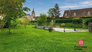 A green lawn with a church and residential buildings in the background. - Gîte with swimming pool at the gateway to the Morvan - Up to 15 people (cussy les forges)