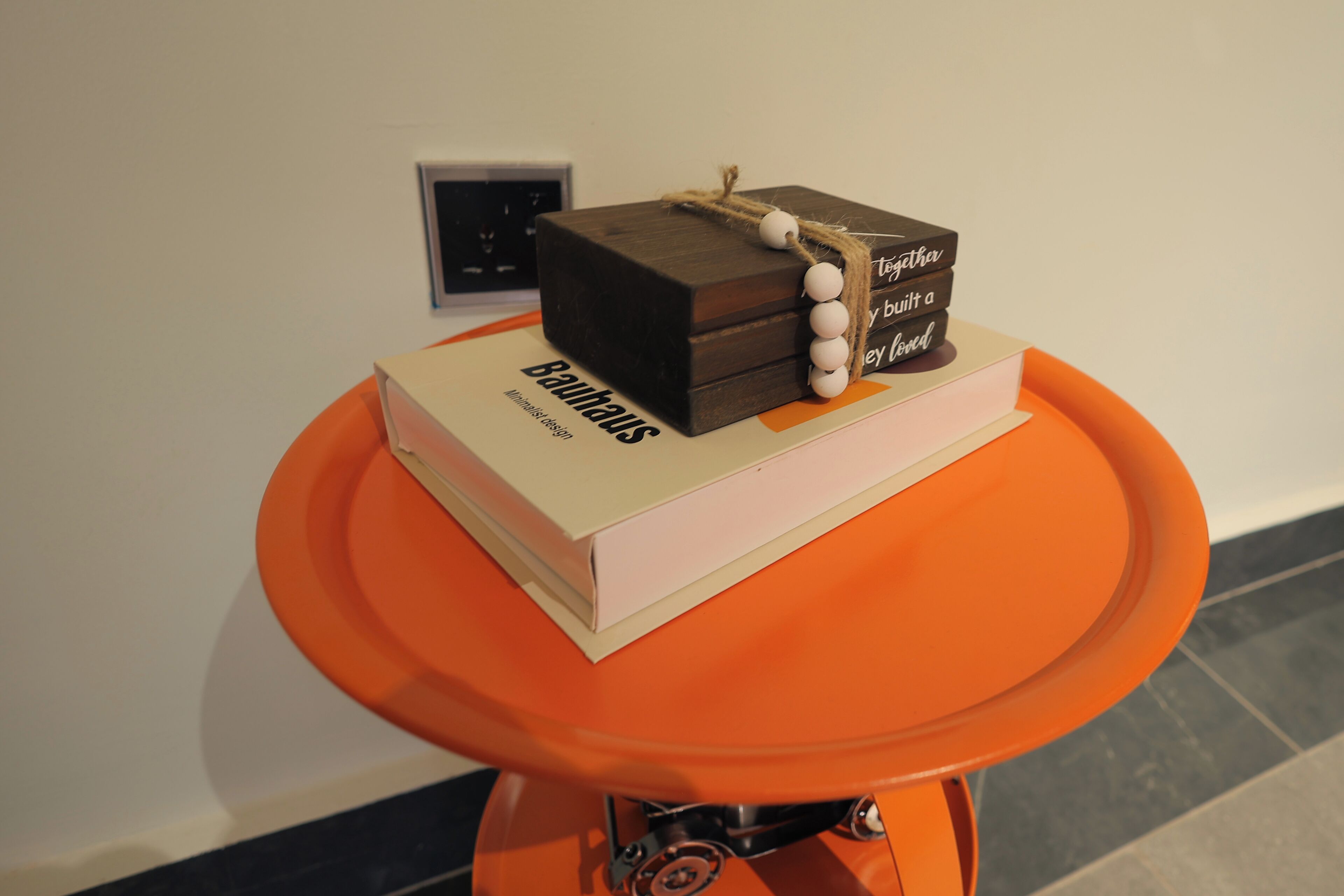 Una mesa con un libro titulado 'Baumhaus' y una pequeña caja de madera con un hilo de cuentas blancas y una etiqueta.