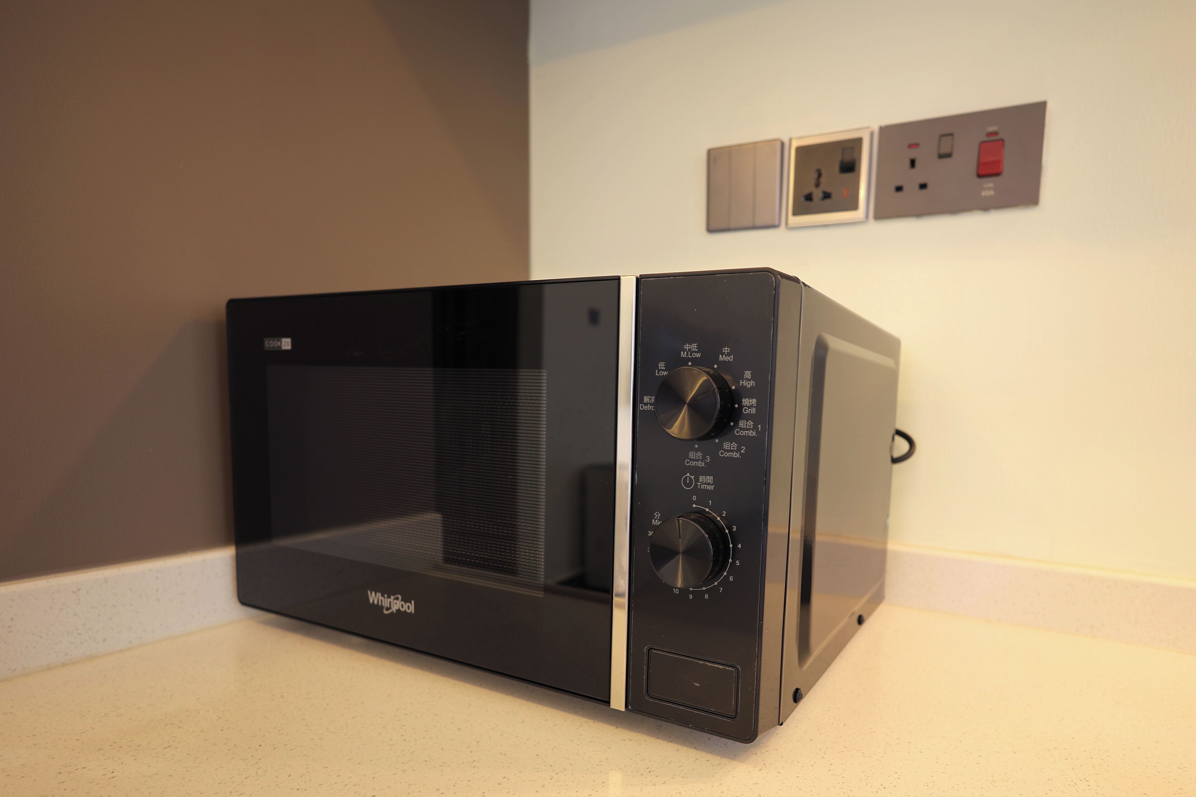 A black Whirlpool microwave oven with control knobs and a digital display, placed on a kitchen countertop.