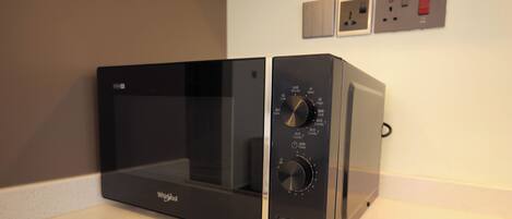 A black Whirlpool microwave oven with control knobs and a digital display, placed on a kitchen countertop.