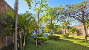A well-maintained courtyard with a swimming pool, palm trees, and a brick building in the background. - Weekend or vacation home, with pool and large garden. (Tlayecac)