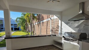 A modern kitchen with a large window, a brick wall, and a grill. - Weekend or vacation home, with pool and large garden. (Tlayecac)