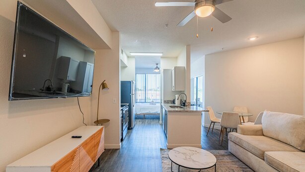 A modern living room with a flat-screen TV, a sofa, a coffee table, and a ceiling fan. - Access 3011 (Tempe)