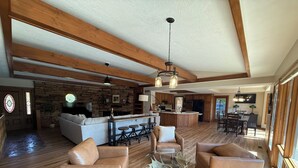 Amplia sala de estar con chimenea de piedra, sofás de cuero y una mesa de centro de vidrio.
