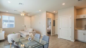 Un salon moderne avec une table à manger en verre, un canapé et un ventilateur de plafond.