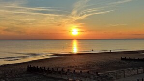 Ein Strand bei Sonnenuntergang, mit klarem Himmel und ruhiger See.