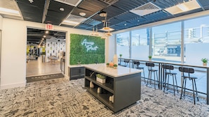 A modern office space with a bar area, a green wall with 'Access Point' signage, and a view of the city through large windows. - Access 3104 (Tempe)