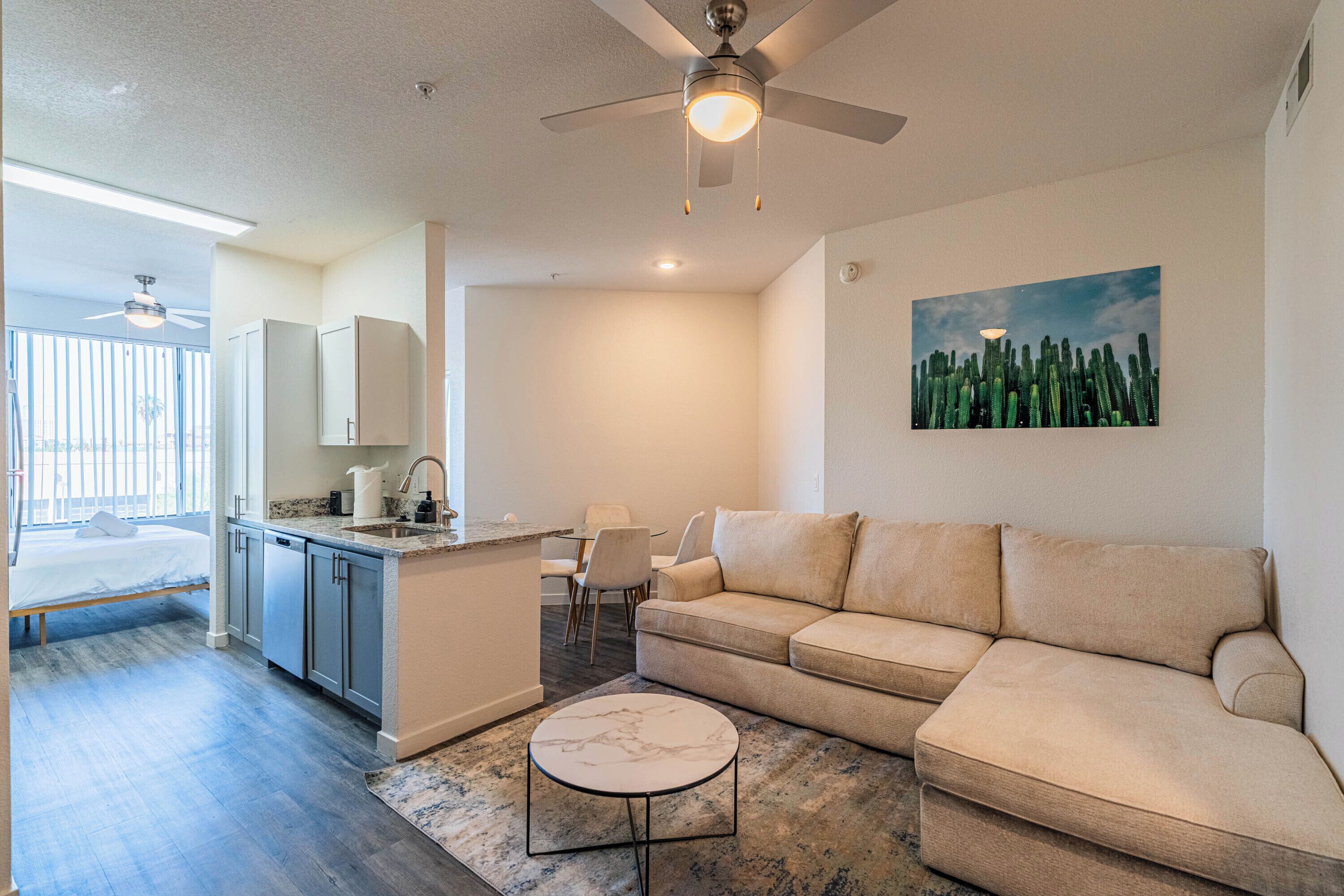 A modern living room with a beige sofa, a marble coffee table, and a ceiling fan.