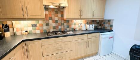 A kitchen with wooden cabinets, a tiled backsplash, a gas stove, a toaster, and a dishwasher.