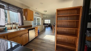 A kitchen with wooden cabinets, a dishwasher, and a sink. There is a dining area with a table and chairs. - Olympic Peninsula Vacation Rental: Close to Water (Sekiu)