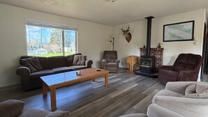 A living room with a sofa, armchairs, a coffee table, a fireplace, and a mounted deer head. - Olympic Peninsula Vacation Rental: Close to Water (Sekiu)