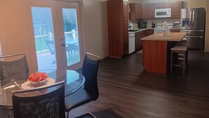 Una cocina moderna con armarios de madera, electrodomésticos de acero inoxidable y un comedor con mesa y sillas de vidrio.