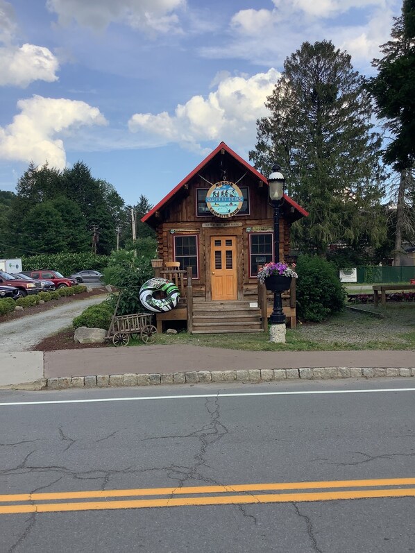 Une cabane rustique en rondins, avec une enseigne indiquant « Roscoe Outfitters » et « Campground Park ».