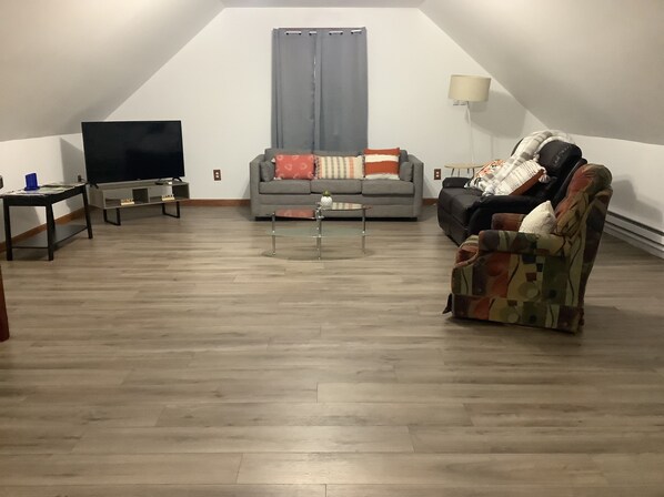 Un salón estilo loft con televisor, sofá y sillón.