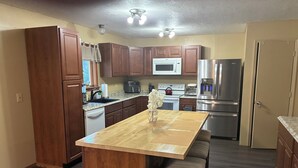 Una cocina con armarios de madera, una isla central, un microondas, un refrigerador y un lavavajillas.