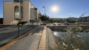 Un immeuble résidentiel doté de balcons, d’un trottoir pavé et d’une zone de stationnement.