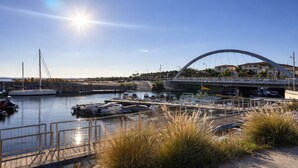 Un port de plaisance avec des bateaux amarrés, un pont et un ciel dégagé.