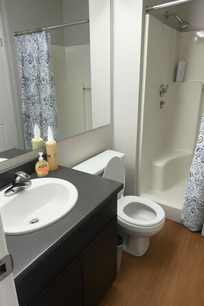 Une salle de bain moderne avec un lavabo, des toilettes et une douche, le tout de couleur blanche.