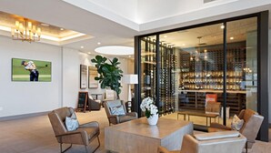 Ein modernes Interieur mit einer Sitzecke, einer großen Pflanze und einem Weinkühlschrank, sichtbar durch Glastüren.
