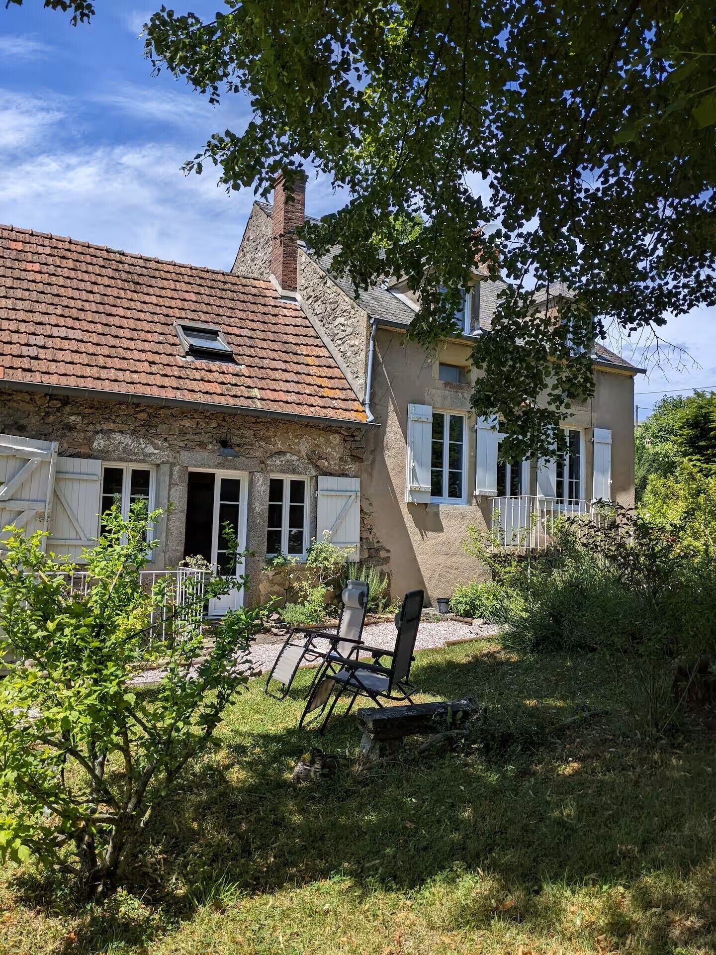 Une maison de campagne à l’aspect rustique, avec une façade en pierre, un toit en tuiles et une petite fenêtre.
