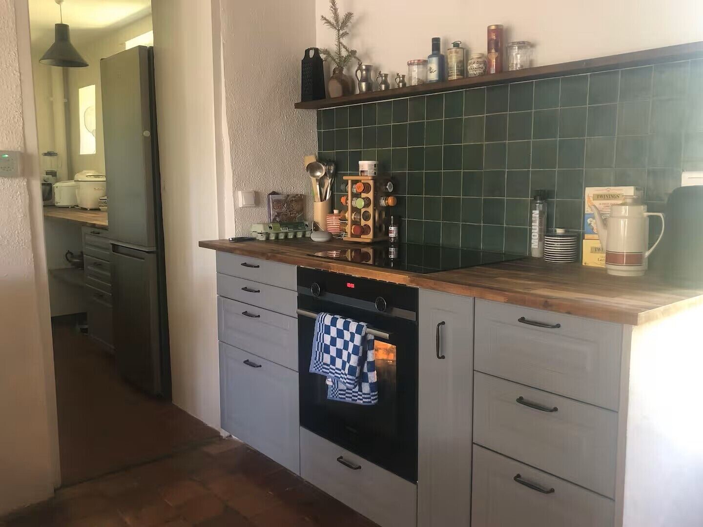 A kitchen with a wooden countertop, a built-in oven, and a green tiled backsplash.