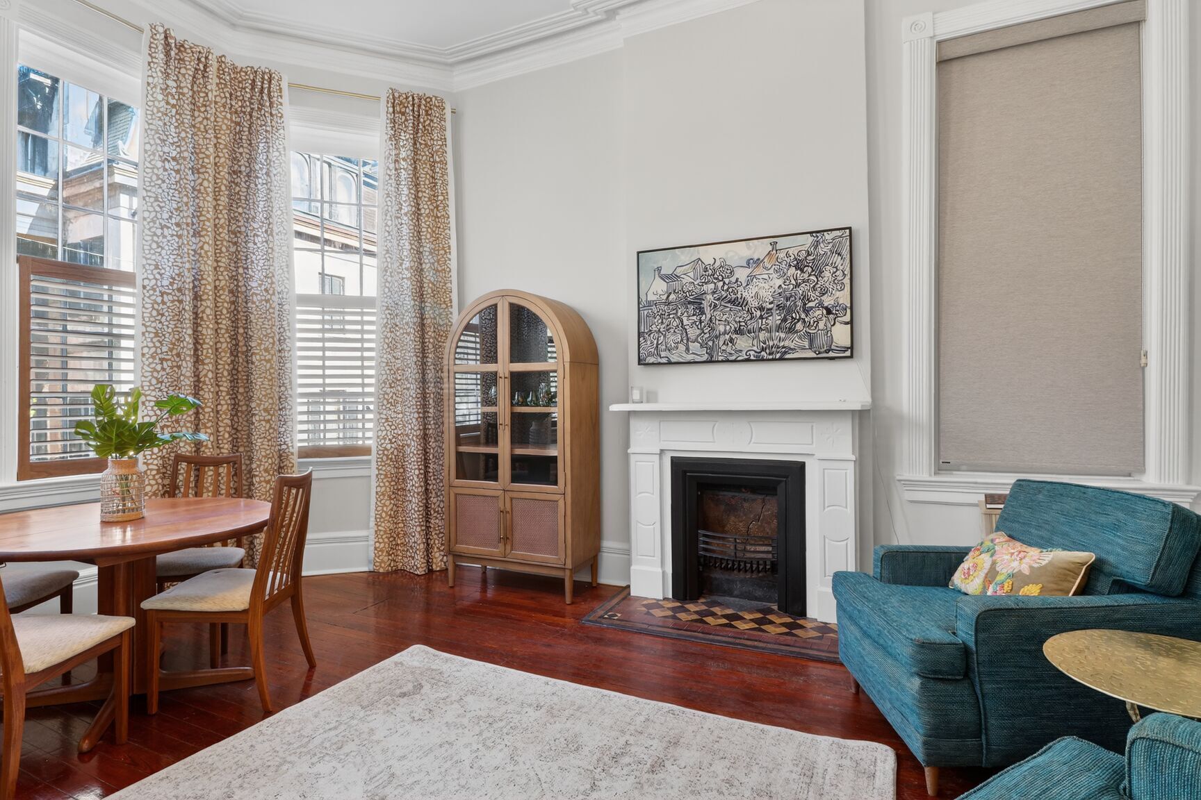 A living room with a fireplace, a dining area with a table and chairs, and a blue sofa.