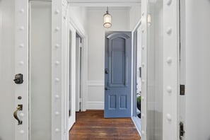 A hallway with a wooden floor, white walls, and a blue door at the end. - Henry Hayme House Parlor Suite Overlooking Orelans Square (Savannah)