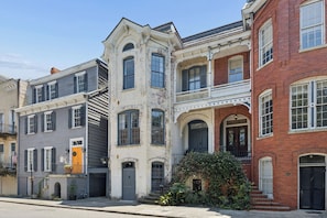 A row of historic townhouses with front porches, a central staircase, and a small garden area. - Henry Hayme House Parlor Suite Overlooking Orelans Square (Savannah)