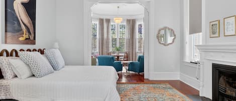 Un dormitorio con una cama grande, un tapete estampado, una chimenea y vistas a un comedor.
