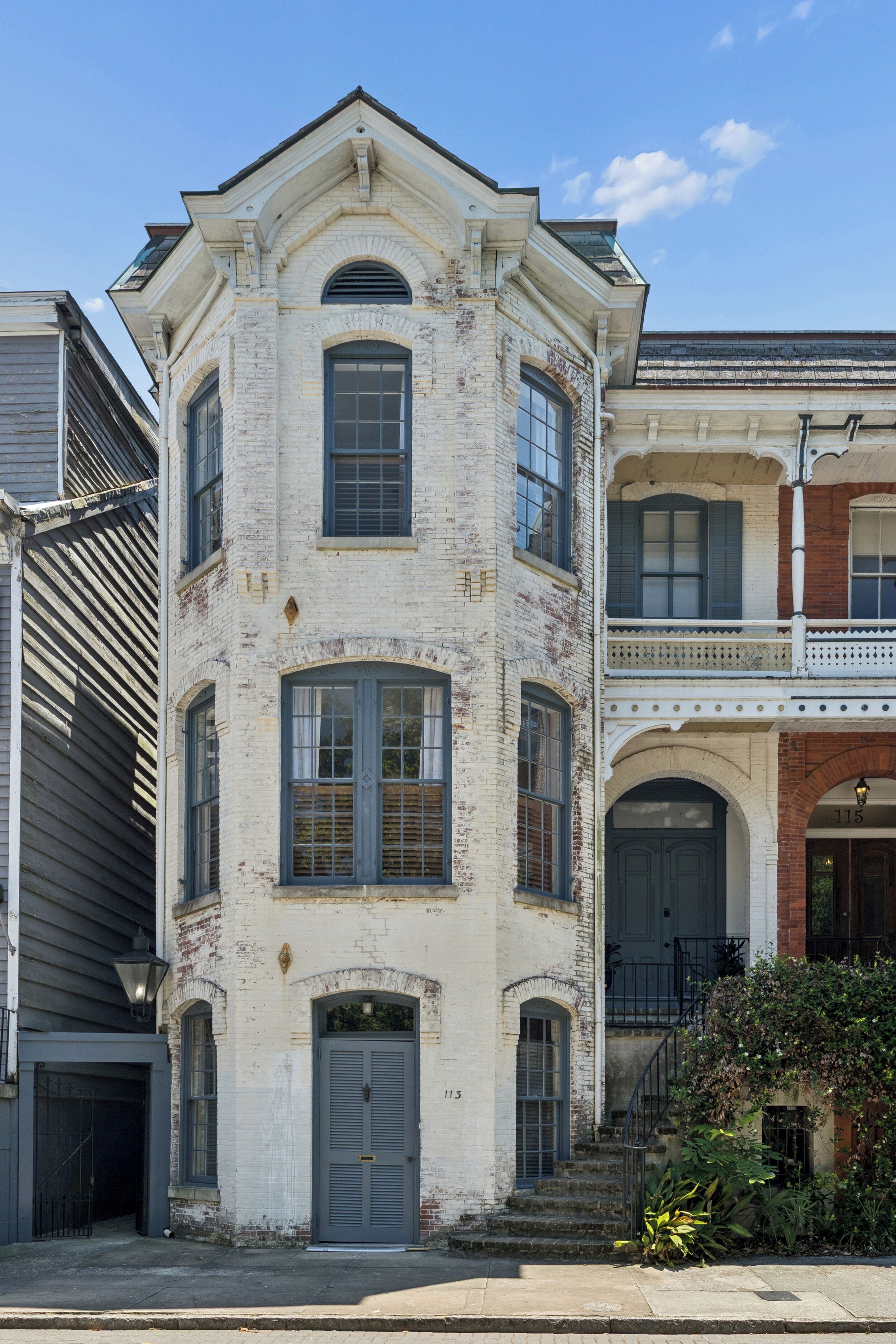 A two-story building with a symmetrical facade, a central entrance with a double door, and a small balcony on the upper floor.