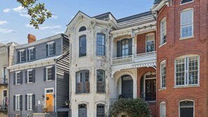 A row of historic townhouses with distinct architectural styles, including a balcony and a front door. - Henry Hayme House Penthouse: Overlooking Orleans Square (Savannah)