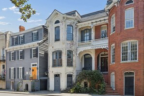 A row of historic townhouses with distinct architectural styles, including a balcony and a front door. - Henry Hayme House Penthouse: Overlooking Orleans Square (Savannah)