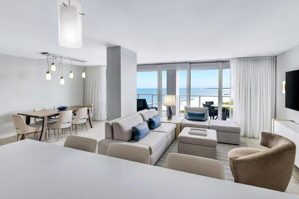 A modern hotel room with a balcony, a dining area, and a living space.