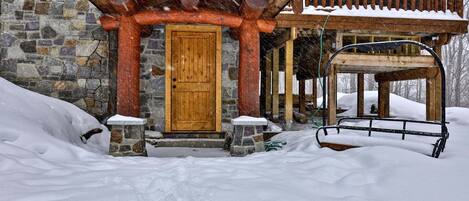 The covered side entry gives guests a sheltered route into the cabin on snowy days.