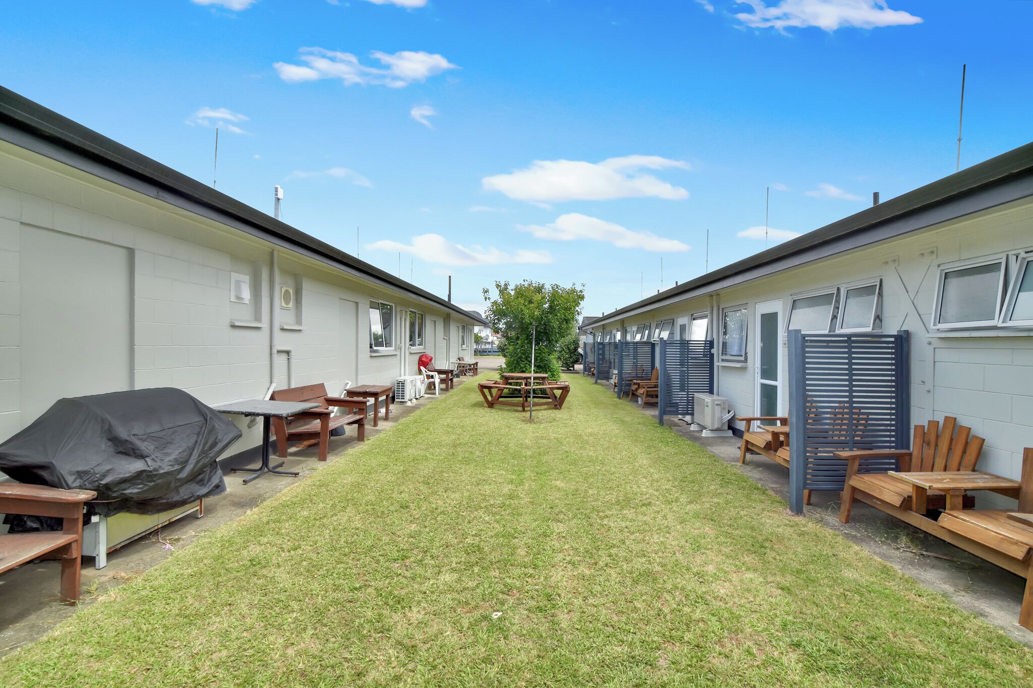 Une rangée de maisons mobiles, avec un espace central gazonné et des meubles d’extérieur.
